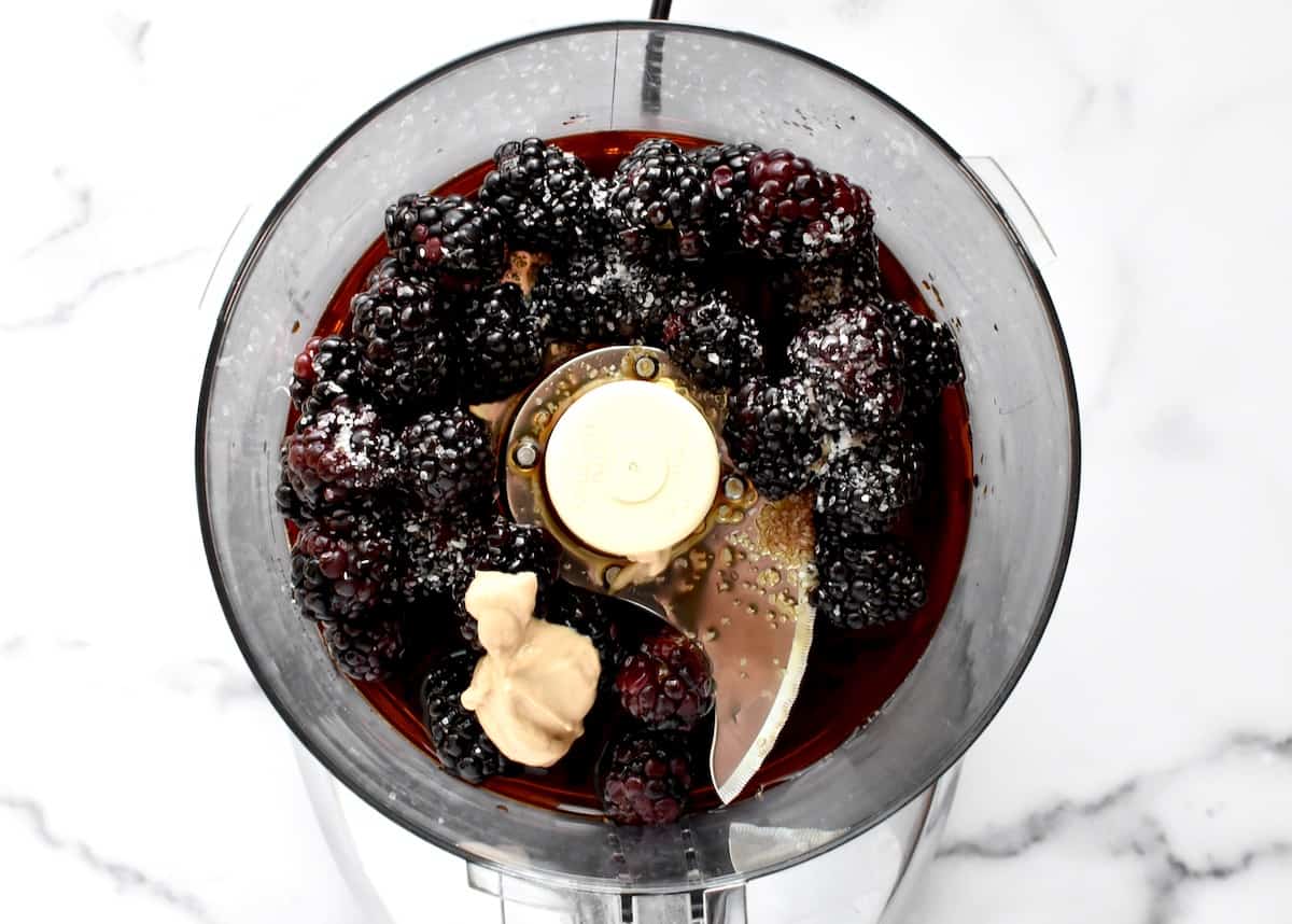 The bowl of a food processor with whole blackberries, dijon, balsamic and salt.