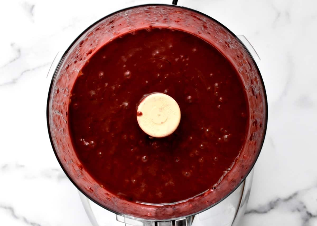 The bowl of a food processor with blackberry balsamic vinaigrette. 