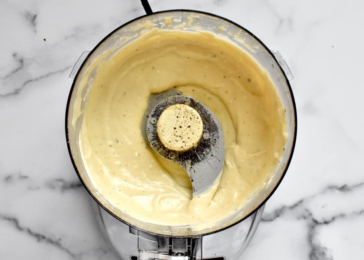 The bowl of a food processor with creamy caesar dressing.