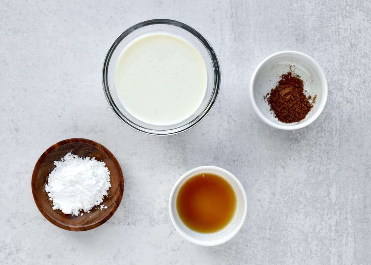 Ingredients for pumpkin spice whipped cream on a grey background.