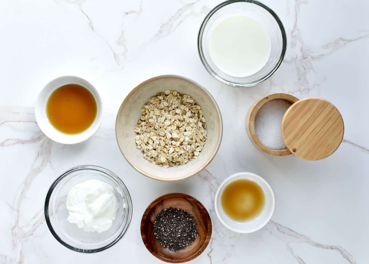 Ingredients for vanilla overnight oats are arranged on a marble background.