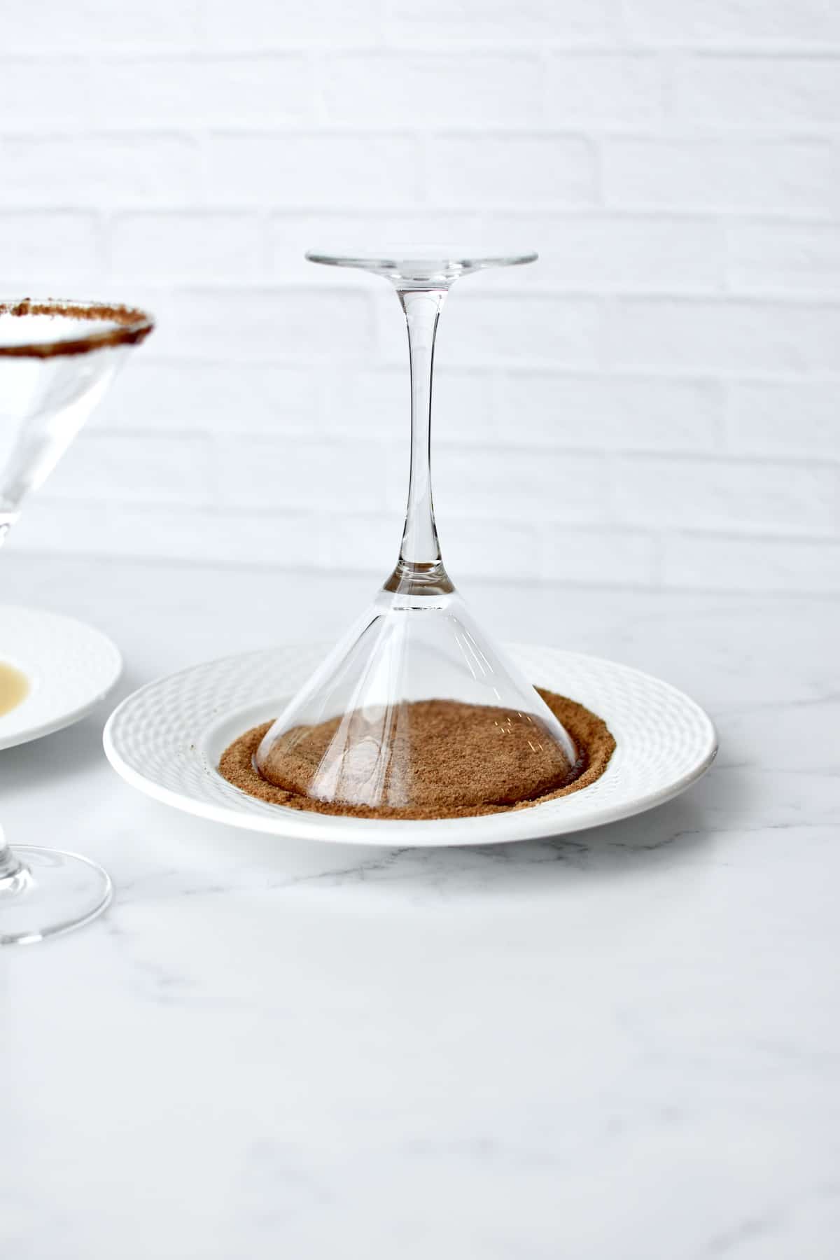 A martini glass being dipped into a plate of coconut sugar.