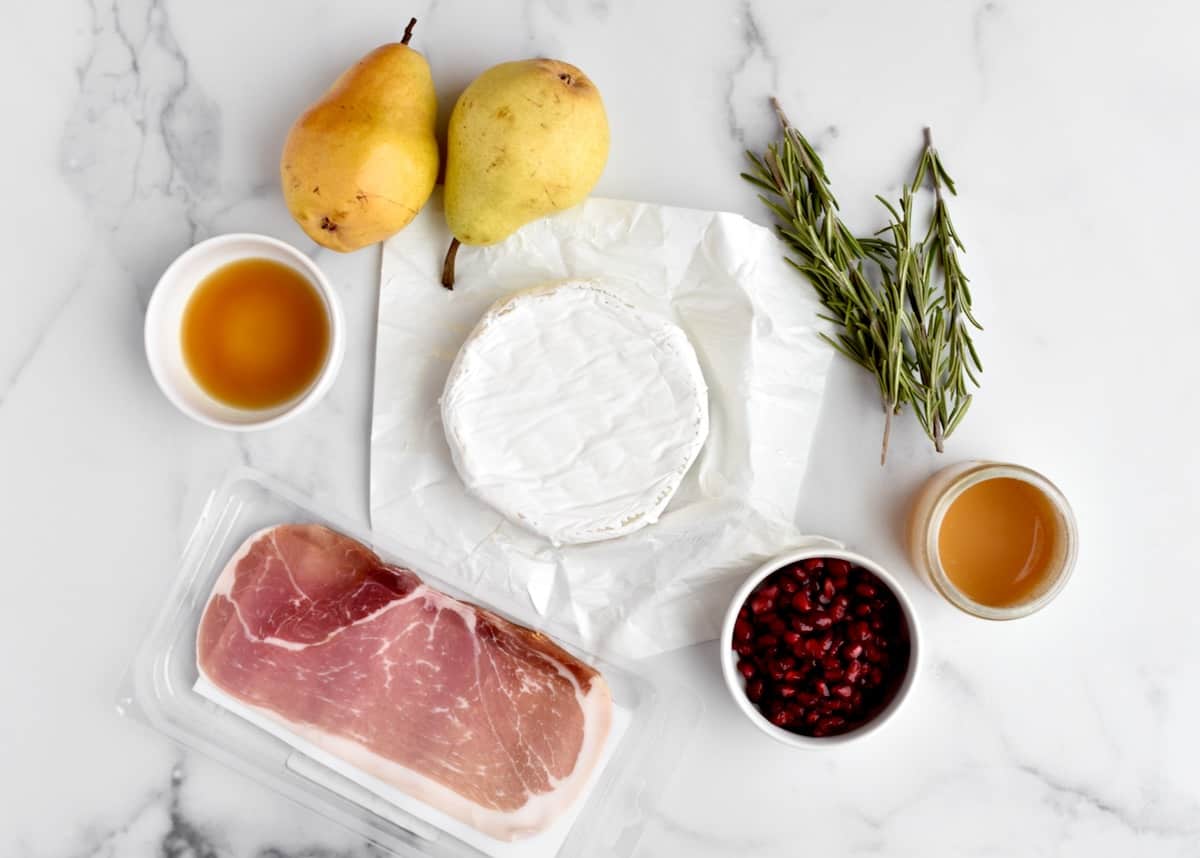 Ingredients for baked brie with pears on a marble background.