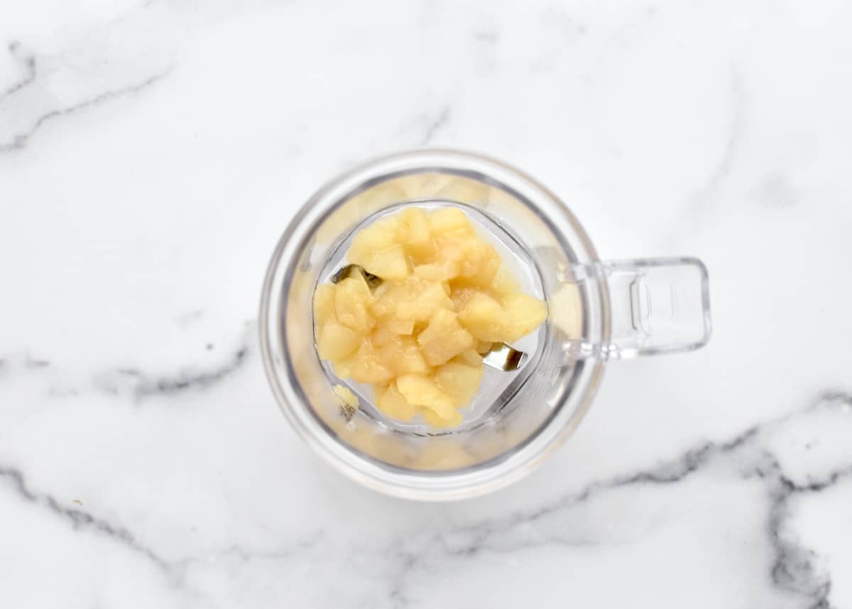 A mini blender with caramelized pears on a marble background.