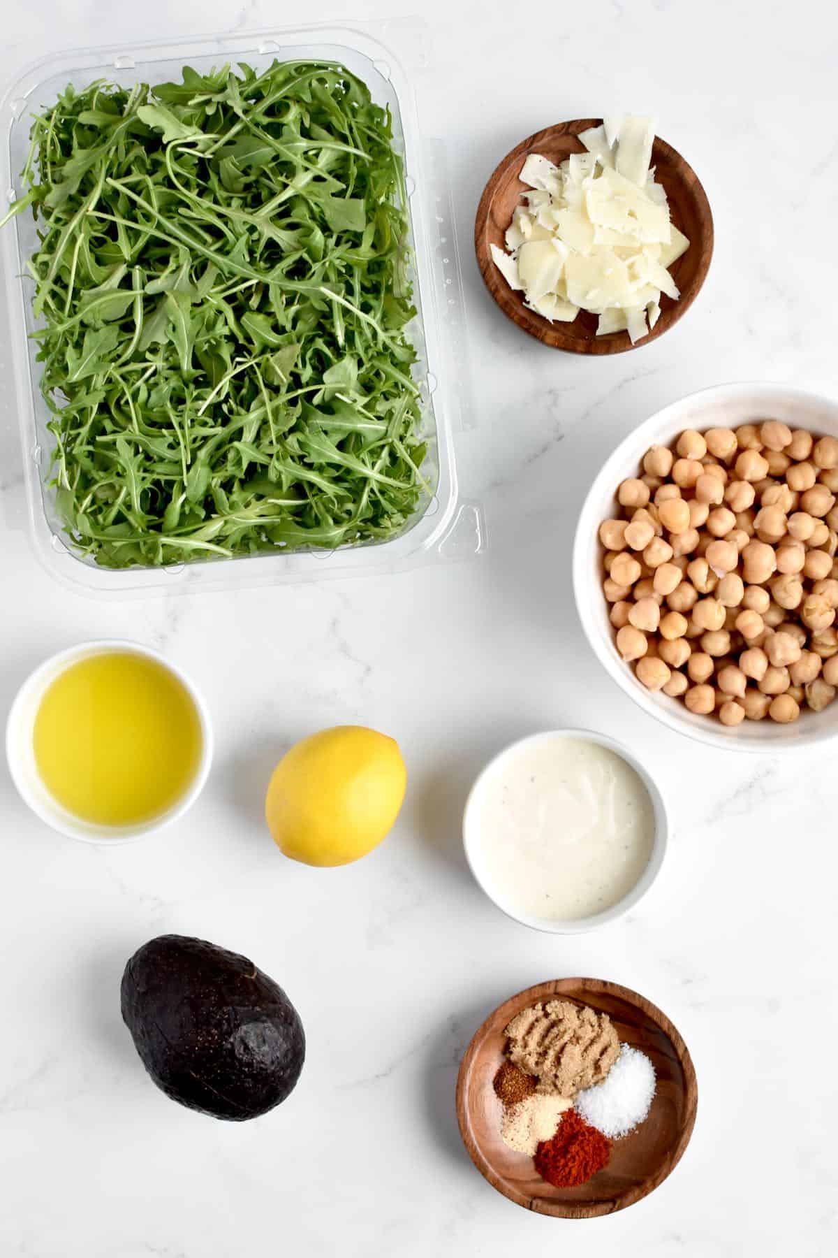 Ingredients for arugula caesar salad on a marble background.