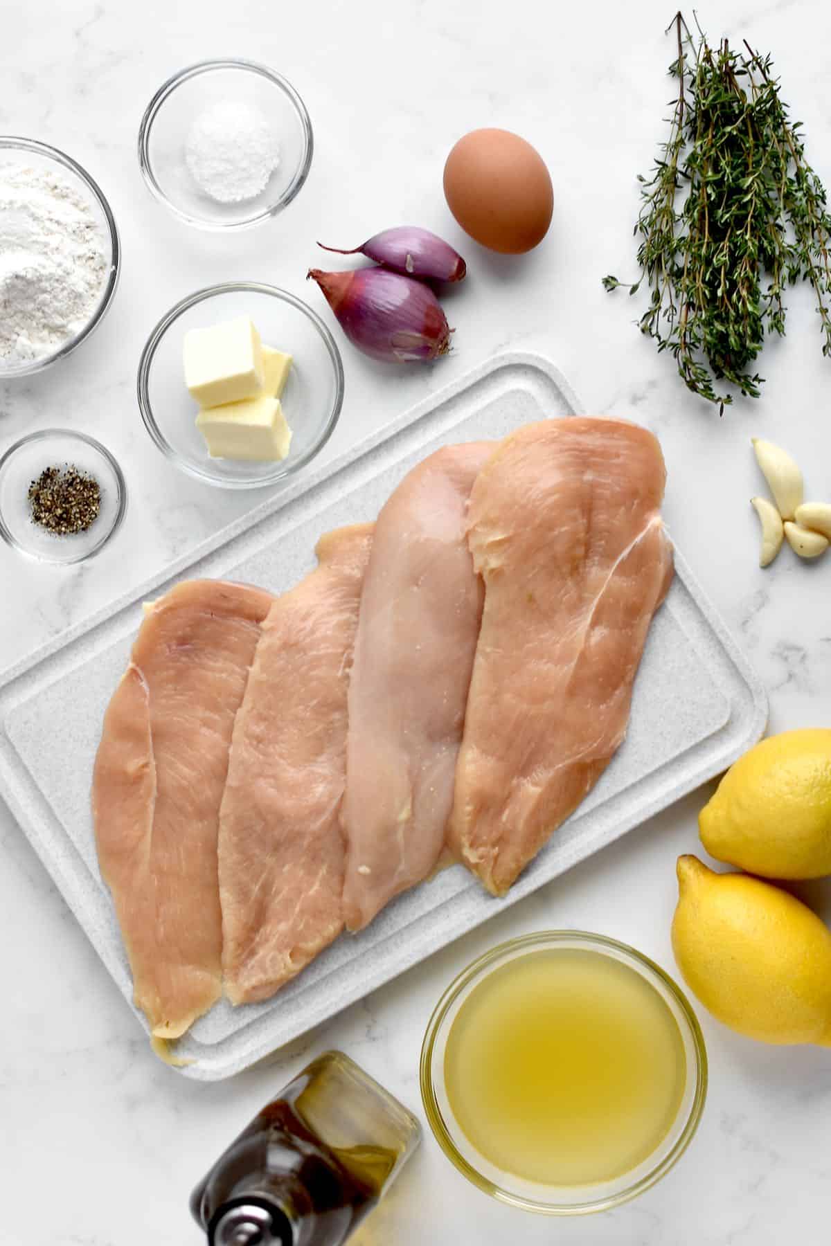 Ingredients for chicken limone on a marble background.