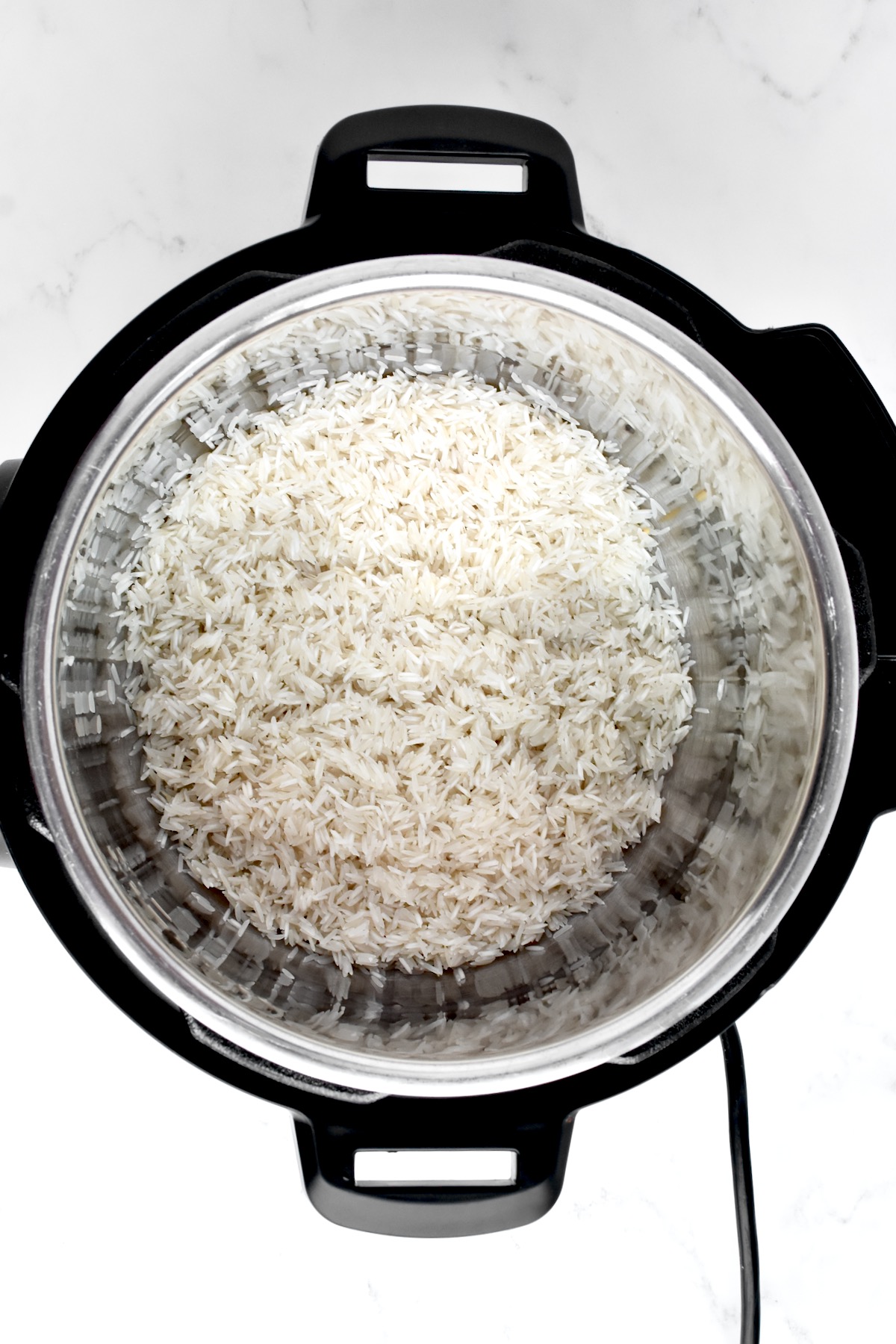 The inside of an instant pot with rinsed basmati rice.