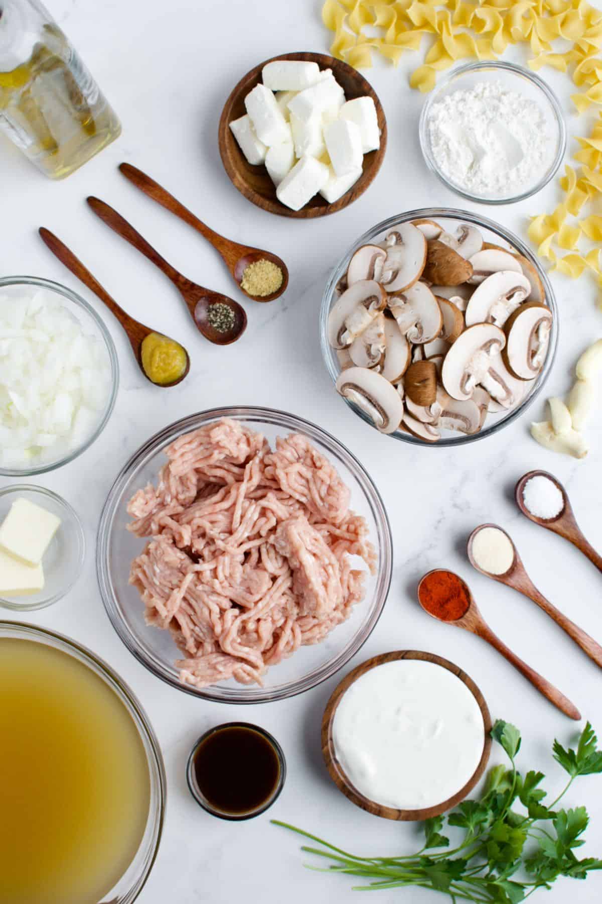 Ingredients for ground chicken stroganoff on a marble background.