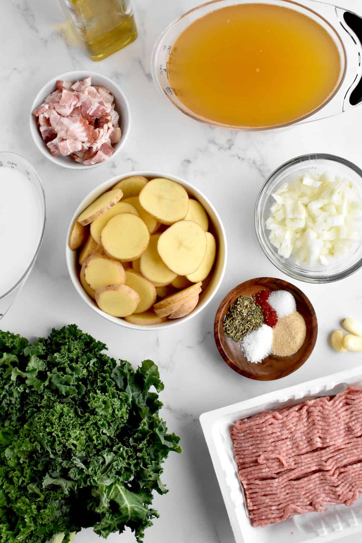 Ingredients for zuppa toscana on a marble background.