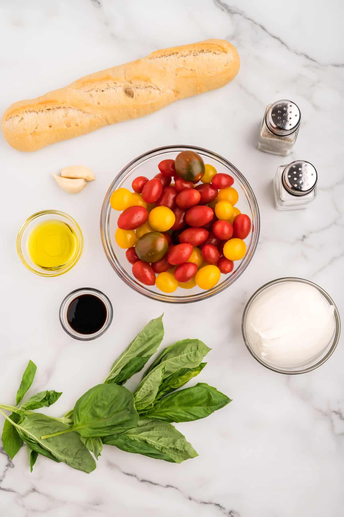 Ingredients for burrata bruschetta on a marble background.