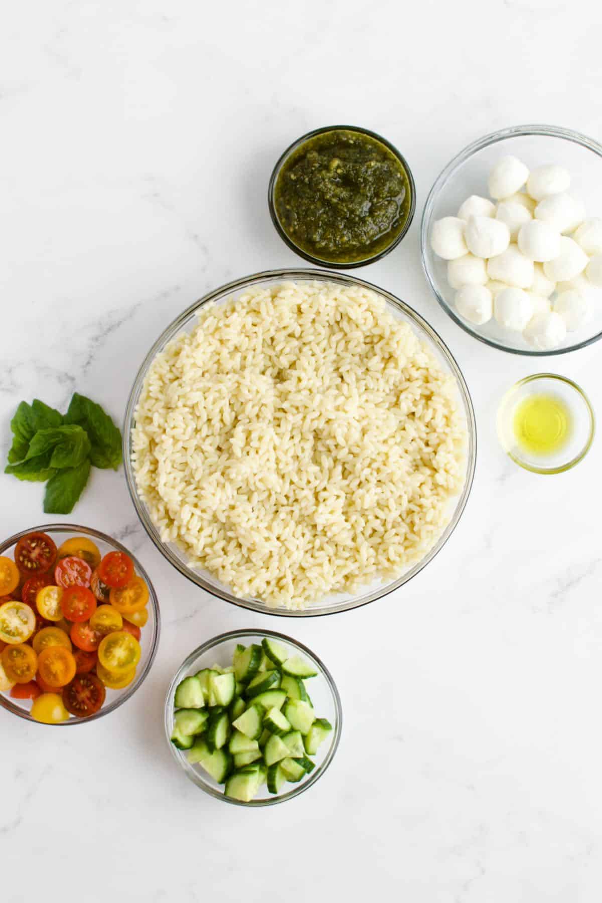 Ingredients for orzo pesto salad on a marble background.