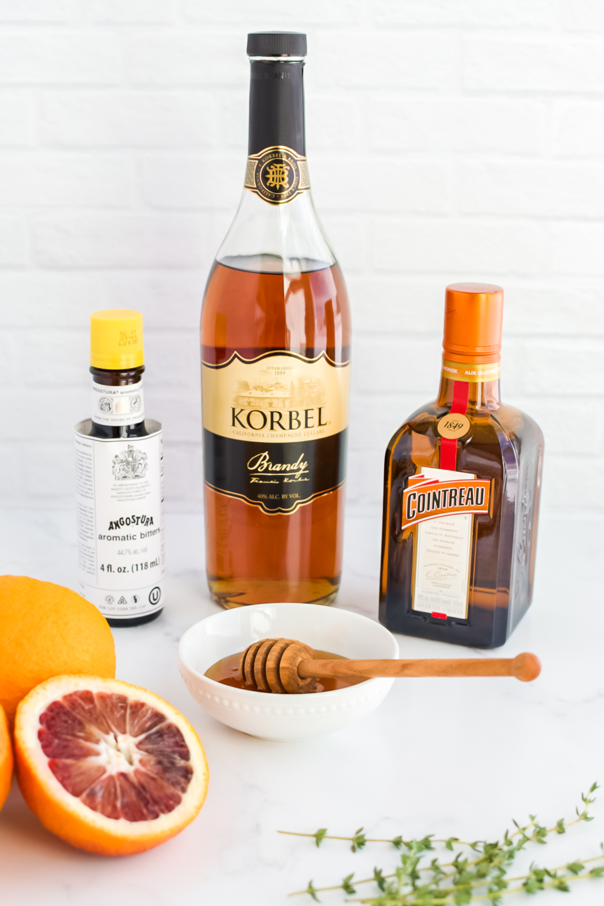 Ingredients for a blood orange honey old fashioned on a marble background.