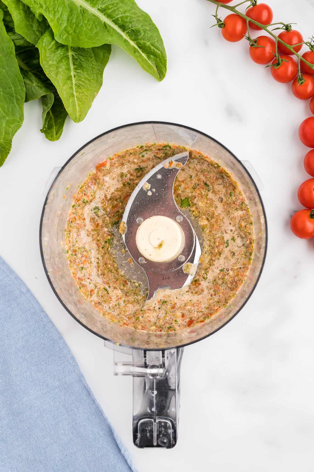 The bowl of a food processor with salsa.