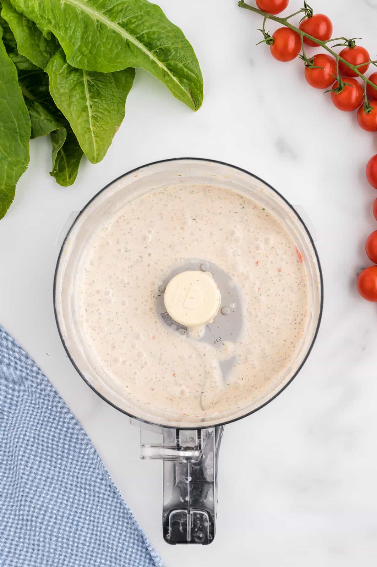 The bowl of a food processor with creamy salsa ranch dressing.