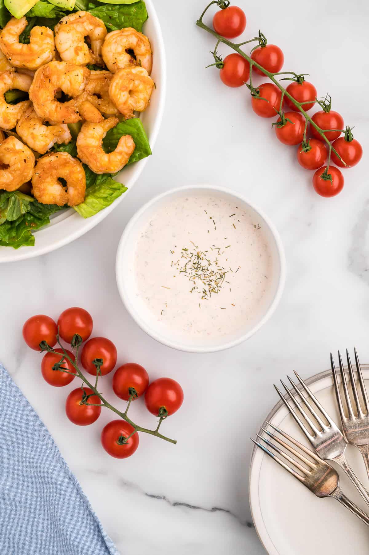 A bowl of salsa ranch dressing, with a shrimp fajita salad and cherry tomatoes off to the side.