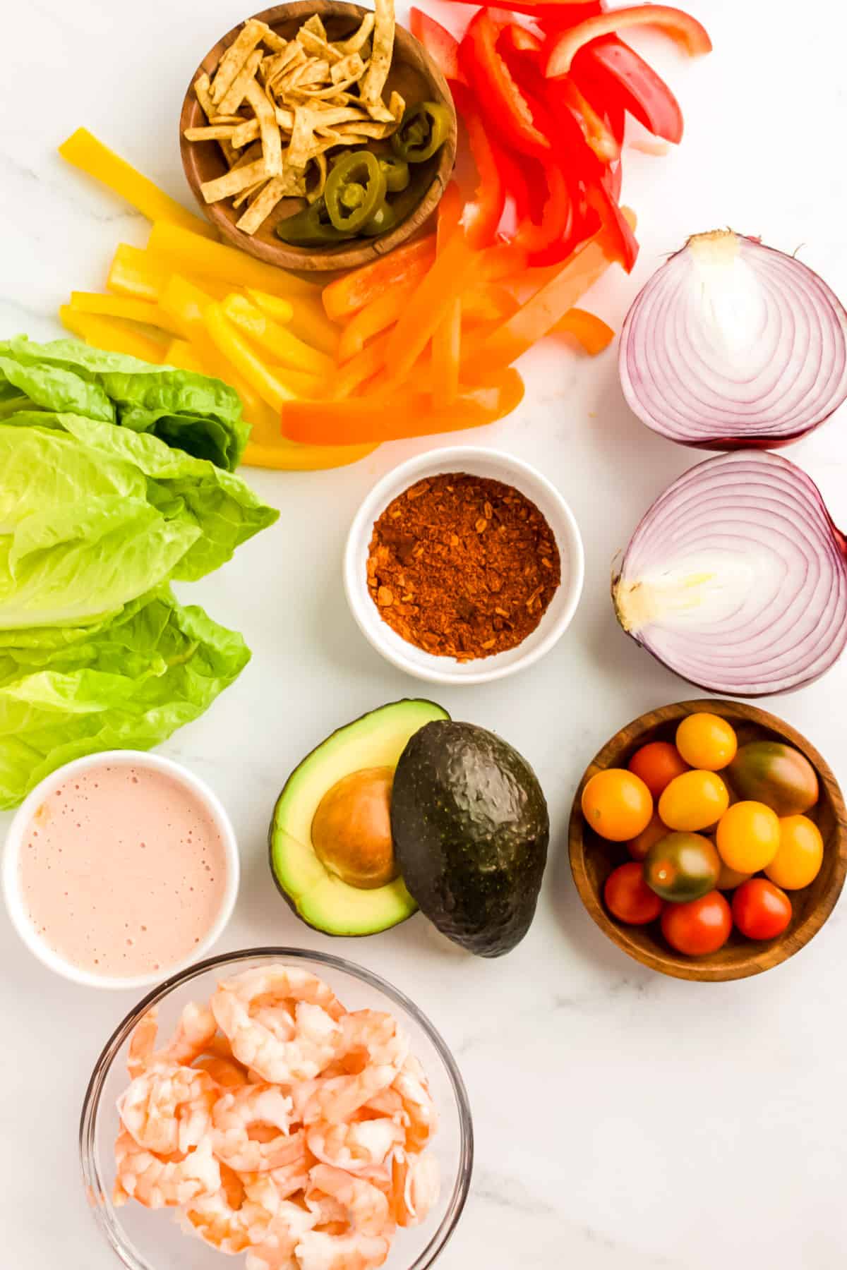 Ingredients for shrimp fajita salad on a marble background.