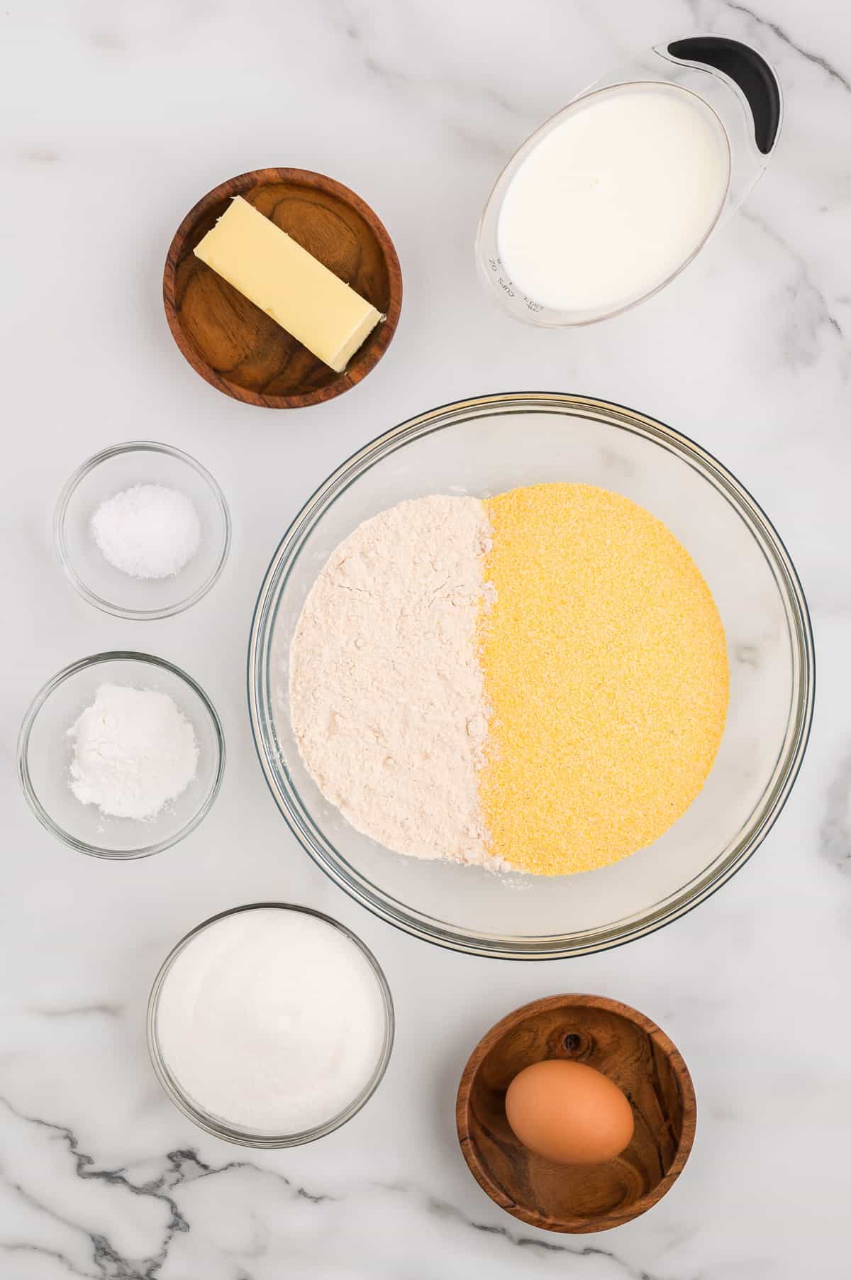 Ingredients for whole grain cornbread on a marble background.