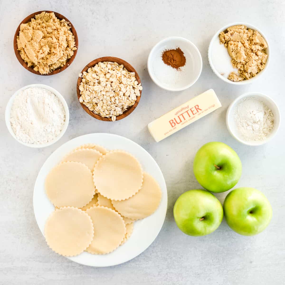 Ingredients for apple crumble tartlets on a grey background.