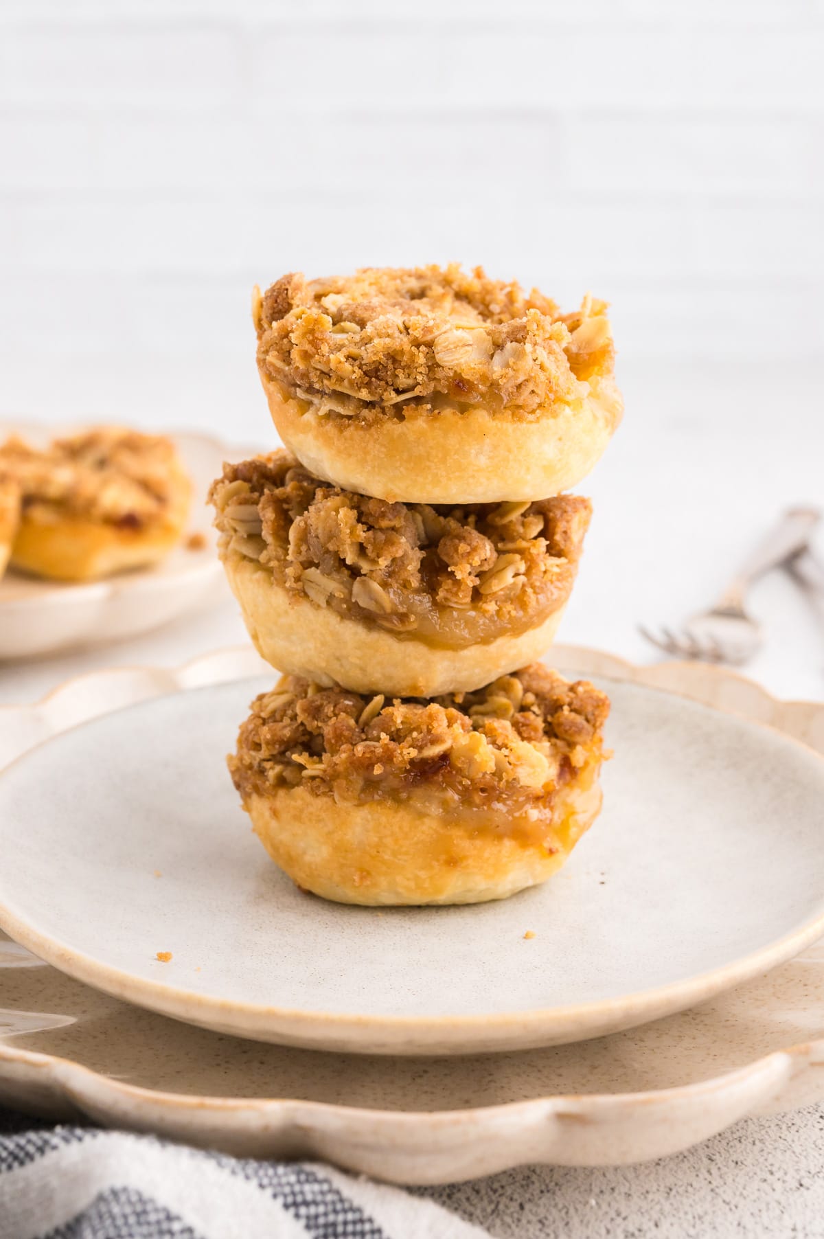 A stack of three apple crumble tartlets, with more tartlets in the background.